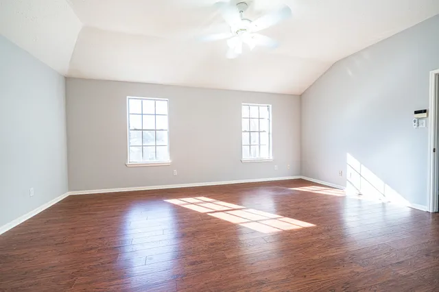 an empty room with wooden floor and windows