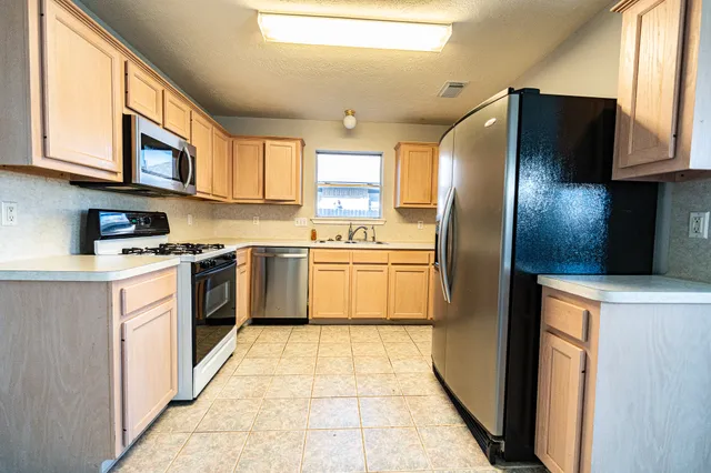 a kitchen with stainless steel appliances granite countertop a stove a sink and a refrigerator