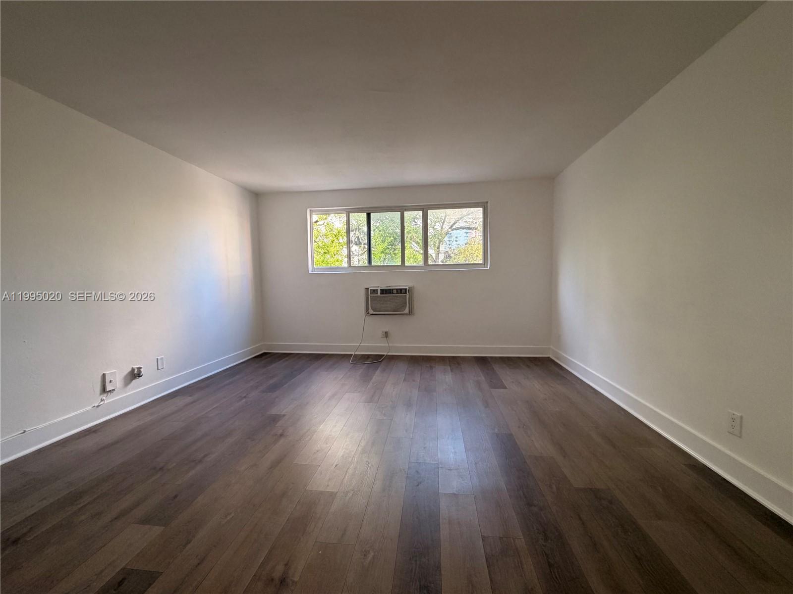 143 Southwest 9th Street, Unit 105 Miami, FL 33130 - Photo 7 of 20 an empty room with wooden floor and windows