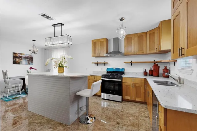 a kitchen with stainless steel appliances granite countertop a sink a stove and a wooden floors
