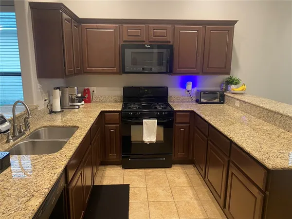 a kitchen with granite countertop stainless steel appliances a stove sink and microwave