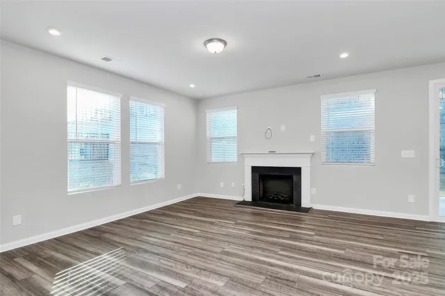 an empty room with windows and fireplace