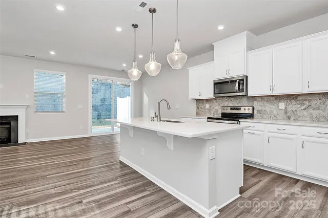 a kitchen with kitchen island granite countertop a sink cabinets and stainless steel appliances