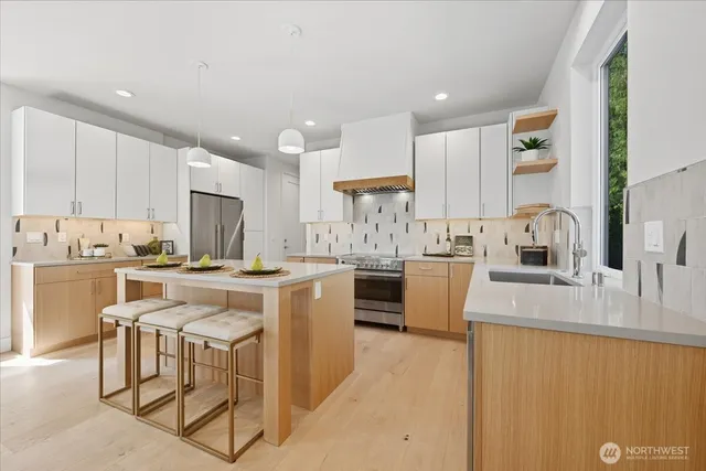 a kitchen with kitchen island a counter top space a sink stainless steel appliances and cabinets
