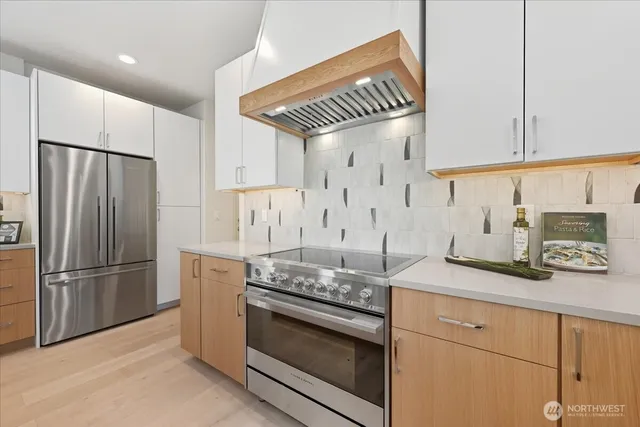 a kitchen with stainless steel appliances granite countertop a stove a refrigerator and a granite counter tops with white cabinets