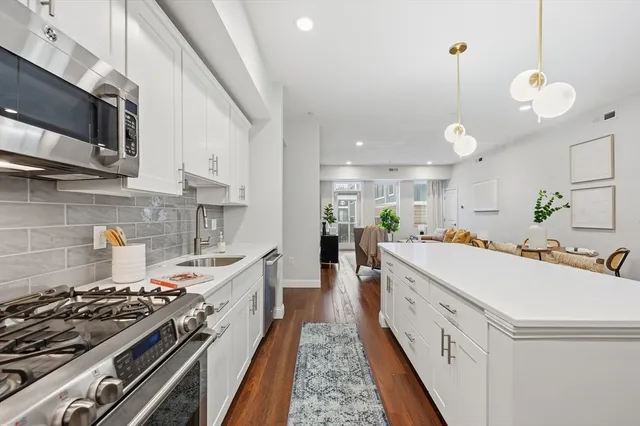 a large kitchen with stainless steel appliances a stove a sink dishwasher and a microwave with wooden floor