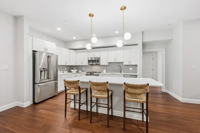 a kitchen with stainless steel appliances a dining table chairs stove and refrigerator