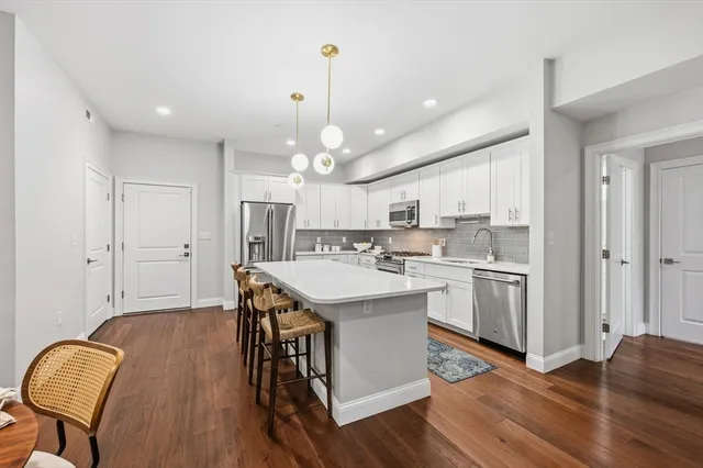 a kitchen with stainless steel appliances a dining table chairs stove refrigerator and cabinets