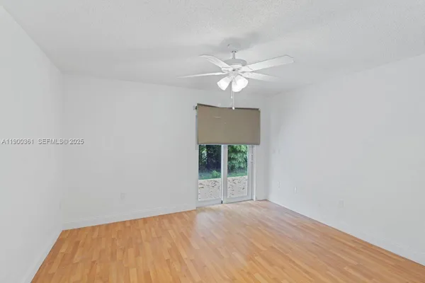 an empty room with wooden floor fan and windows