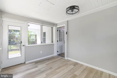 a view of an empty room with window and wooden floor