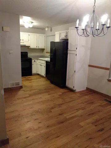 a kitchen with stainless steel appliances granite countertop a refrigerator a sink dishwasher a stove and white cabinets