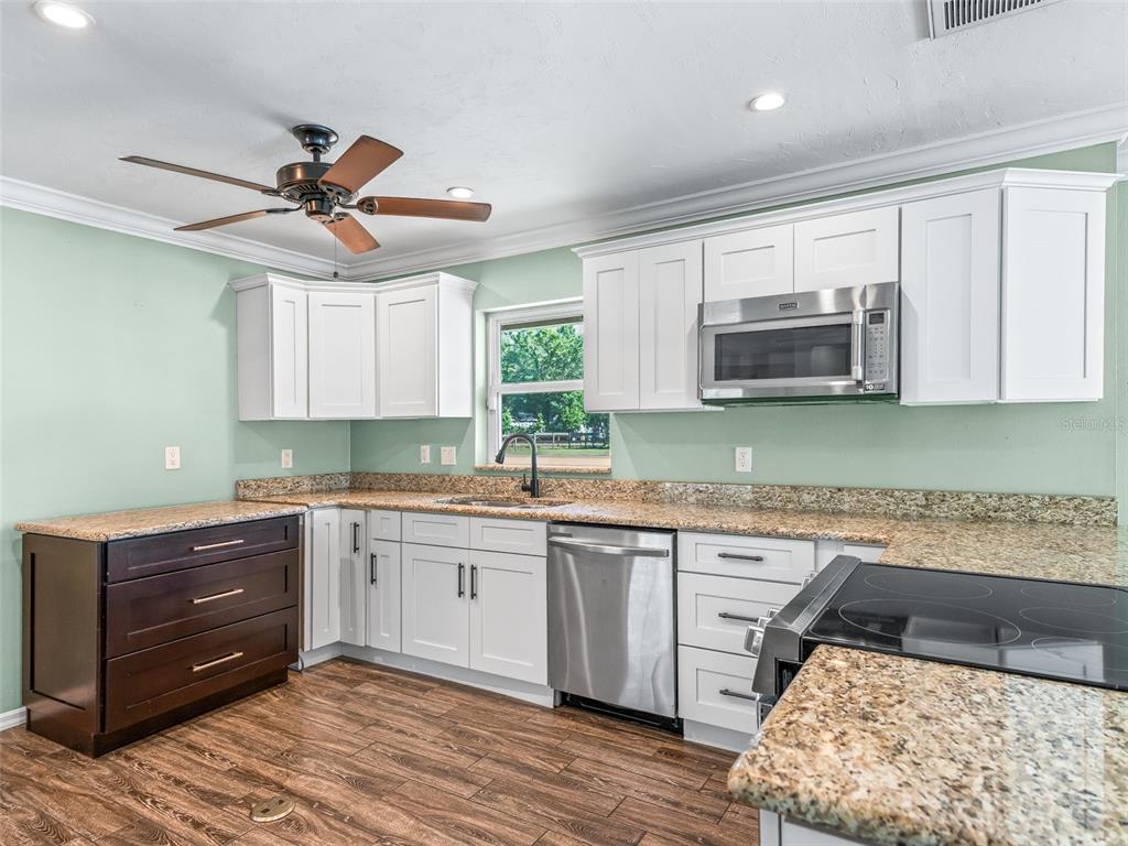 2405 Southeast 157th Lane Road Summerfield, FL 34491 - Photo 14 of 35 a kitchen with kitchen island granite countertop a sink cabinets and stainless steel appliances