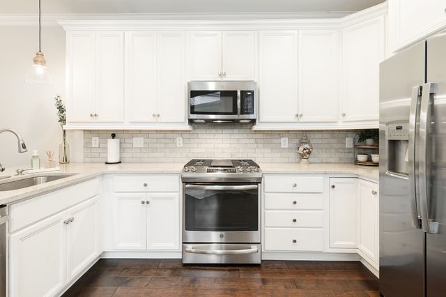 a kitchen with stainless steel appliances white cabinets and a sink