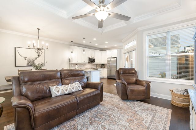 a living room with furniture kitchen view and a chandelier