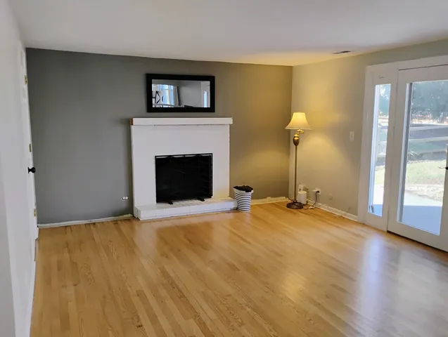 a view of empty room with fireplace and wooden floor