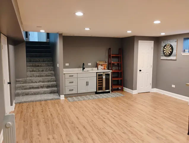 a view of a kitchen with kitchen island a sink wooden floor and stainless steel appliances