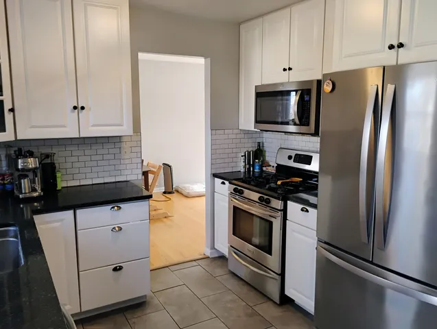a kitchen with granite countertop white cabinets and stainless steel appliances