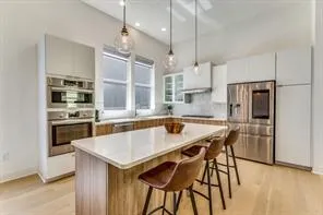 a kitchen with stainless steel appliances granite countertop a kitchen island a stove a refrigerator a oven a sink and a dining table with wooden floor