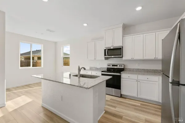 a kitchen with granite countertop white cabinets and stainless steel appliances