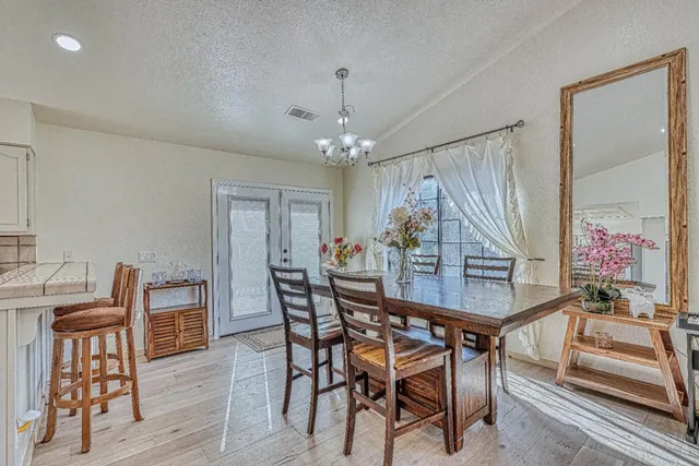 a dining room with wooden floor a chandelier a glass table and chairs