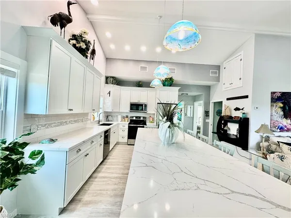a large white kitchen with lots of counter space furniture and a chandelier