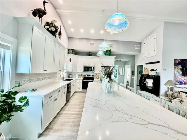 a large white kitchen with lots of counter space furniture and a chandelier