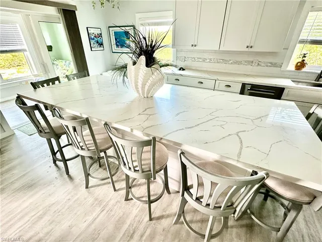 a kitchen with stainless steel appliances kitchen island granite countertop a table chairs and a wooden floor