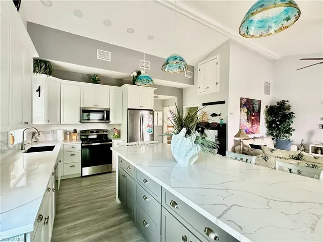 a kitchen with stainless steel appliances kitchen island granite countertop a stove refrigerator and cabinets