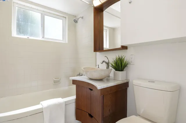 a bathroom with a granite countertop sink a toilet a mirror and bathtub