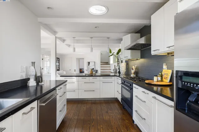 a kitchen with a sink dishwasher stove and white cabinets