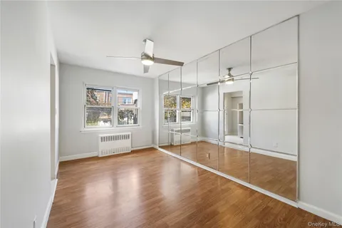 a view of empty room with wooden floor and fan