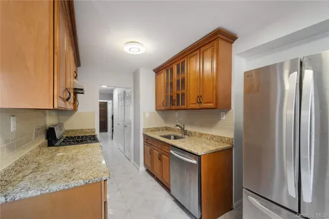 a kitchen with stainless steel appliances granite countertop a refrigerator a stove and a sink with wooden cabinets