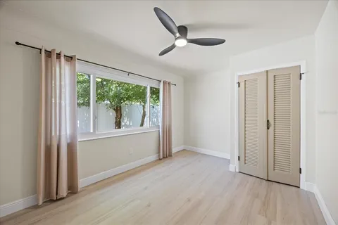 a view of a big room with wooden floor a ceiling fan and windows