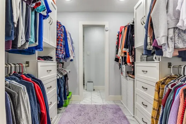 a view of walk in closet with clothes and shoes