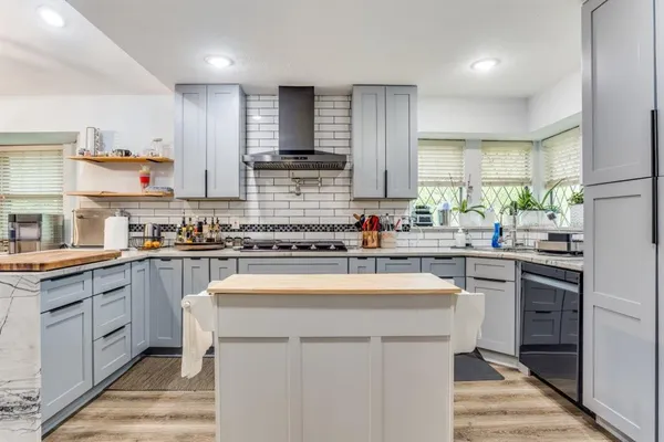 a kitchen with stainless steel appliances kitchen island granite countertop a sink stove refrigerator and cabinets