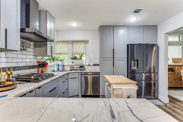 a kitchen with stainless steel appliances a refrigerator a sink a stove and cabinets
