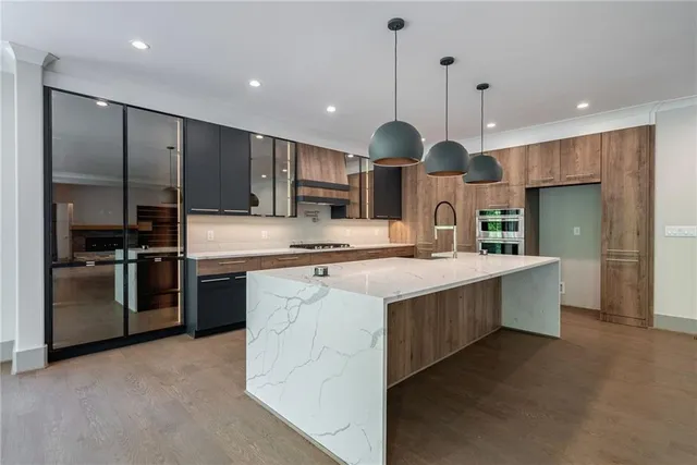 a large kitchen with a large counter top a sink stainless steel appliances and cabinets