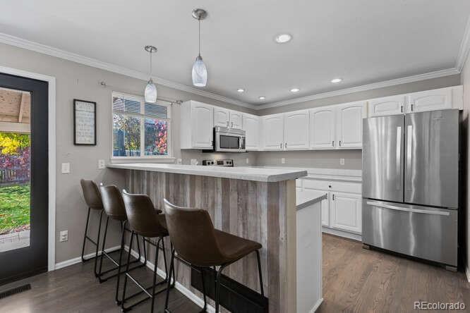 8354 Dove Ridge Way Parker, CO 80134 - Photo 13 of 38 a kitchen with stainless steel appliances granite countertop a refrigerator a sink dishwasher a stove and a dining table with wooden floor