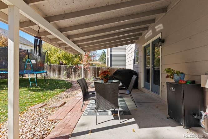 8354 Dove Ridge Way Parker, CO 80134 - Photo 37 of 38 a view of a deck with table and chairs potted plants with floor to ceiling window and garden