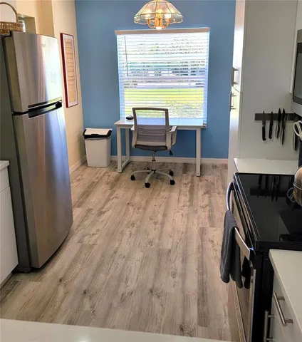 a kitchen with a refrigerator and a wooden floor