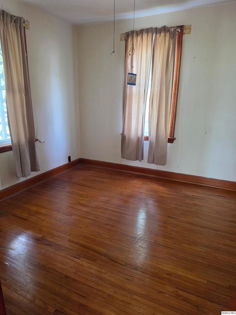 304 West 3rd Street Golden, IL 62339 - Photo 6 of 18 an empty room with wooden floor and windows