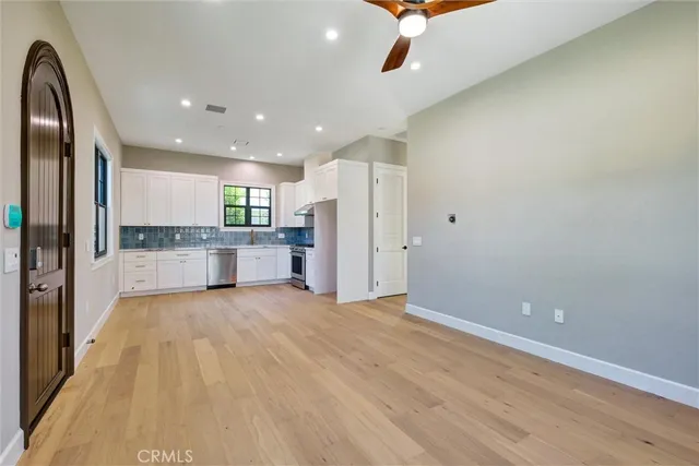 an empty room with windows and kitchen view