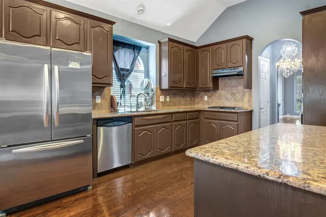 a kitchen with stainless steel appliances granite countertop a sink a stove and a refrigerator