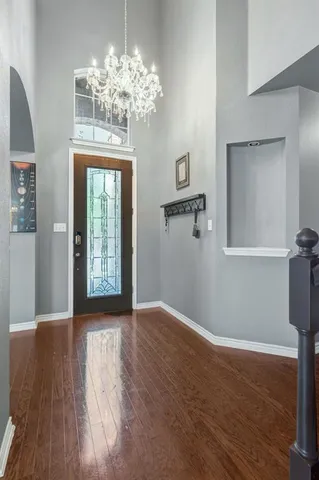 a view of a big room with wooden floor chandelier and windows