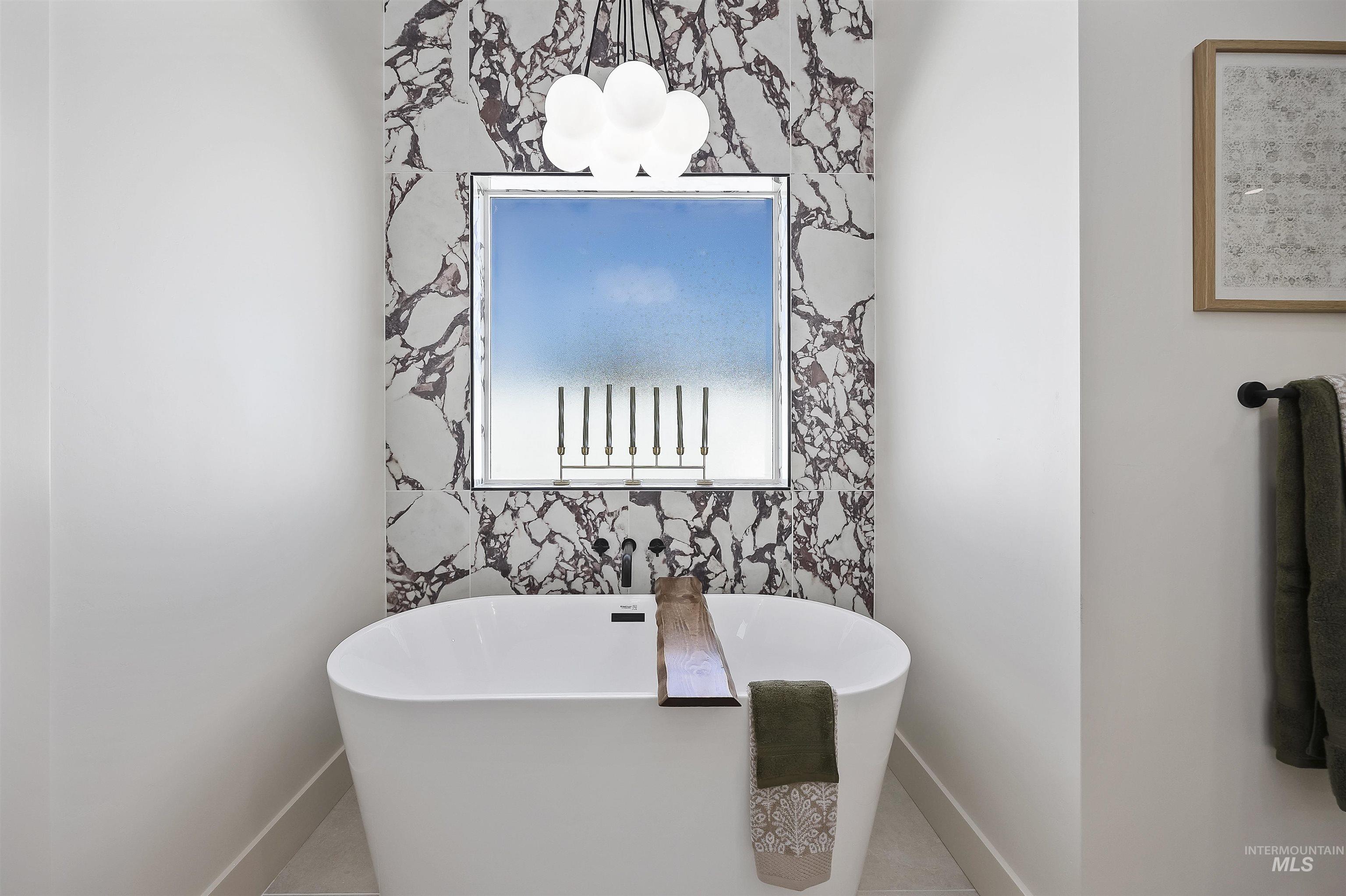 2017 Sparrow Street Rupert, ID 83350 - Photo 17 of 26 Freestanding soaking tub with a wall-mounted faucet, framed window, and marble-patterned wall covering