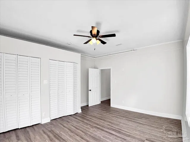 an empty room with wooden floor and ceiling fan