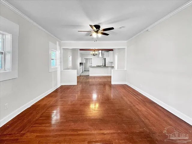 a view of empty room with wooden floor and fan