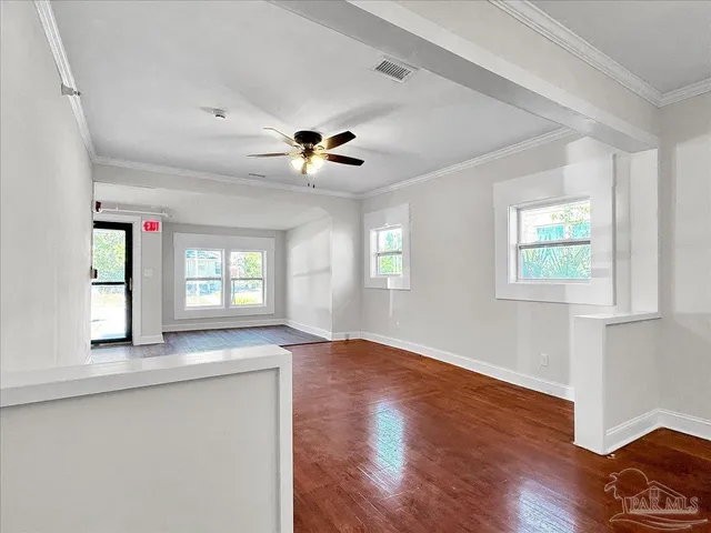 a view of an empty room with a window and wooden floor