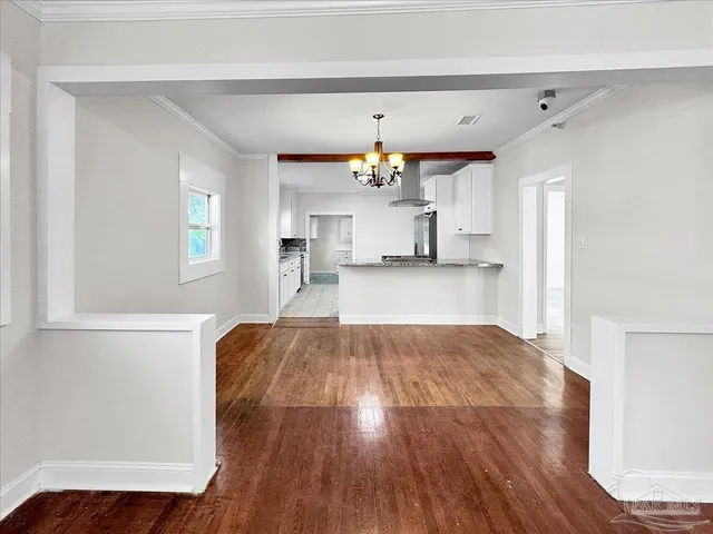 a view of a kitchen and an empty room with a window
