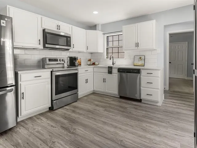 a kitchen with white cabinets stainless steel appliances and sink